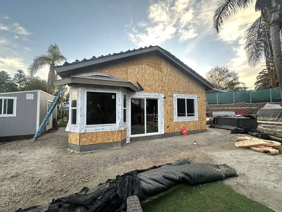 Room addition sheathed in plywood with new windows and a sliding door set in