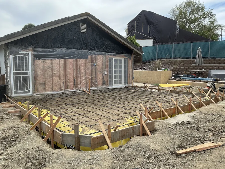 Forms and rebar set for a new concrete slab behind a house
