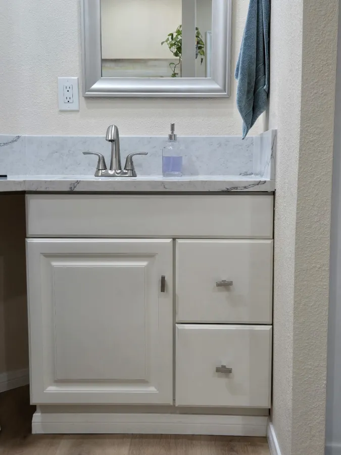 Bathroom vanity with a white cabinet, marble-look top and brushed nickel faucet
