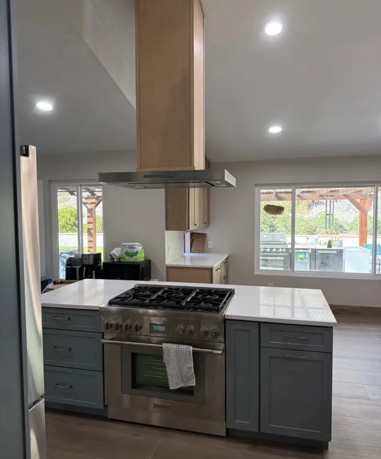 Remodeled kitchen with gray shaker cabinets, a white island and a stainless range